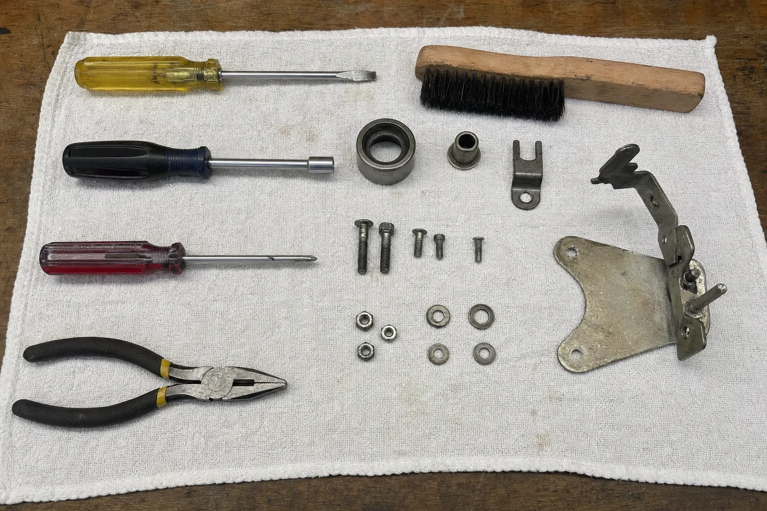 Screwdrivers, pliers and a brush with a hinge bracket, bearing race, bushing and sorted nuts, bolts and washers